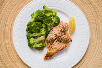 White plate with grilled salmon served with broccoli and lemon. Healthy food for family. Home dinner. Vegetarian diet diet.