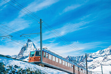Red train running towards gornergrat station on snowy mountain against sky