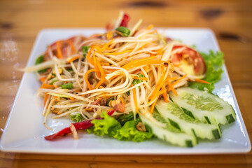 A plate of vegetable Thai papaya salad Som Tam. Remaining Asian cuisine