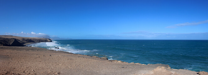 wide panoramic view over the surfing beach and cliffs of la pared on the island of fuerteventura with a clear blue sky