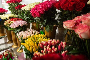Many different colors on the stand table in the flower shop. Showcase. Background of mix of flowers. Beautiful flowers for catalog or online store. Floral shop and delivery concept.