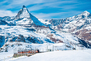 Red train climbing up to Gornergrat station with view of Matterhorn against clear blue sky. Beautiful Zermatt.  - obrazy, fototapety, plakaty
