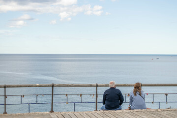 A man and a woman sitting looking at the sea