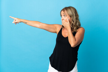 Fototapeta premium Middle aged blonde woman over isolated background with surprise expression while pointing side