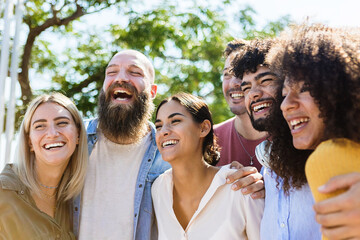 Young group of diverse friends having fun in a sunny day - Multiracial best friends enjoying time together outdoors - United millennial people laughing - Powered by Adobe