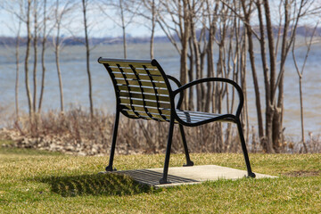 Fototapeta premium Metal bench in a park looking out onto the water
