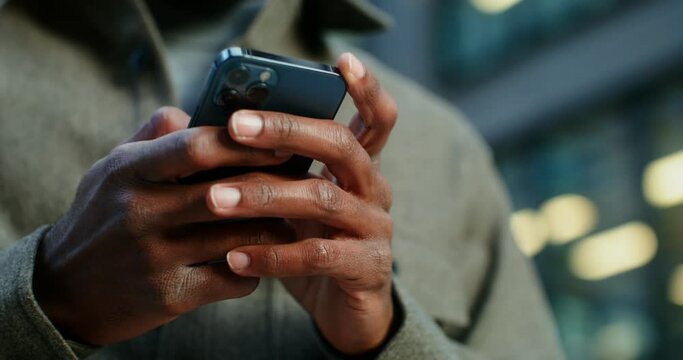 African-American man uses a mobile phone standing near a building in Evening