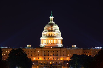 United States Capital Building at night with spot lights illuminating the dome.