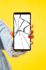 Big smartphone with broken screen. A woman holds a phone in her hand with cracks on the screen. The girl with the broken mobile phone. Smartphone repair.