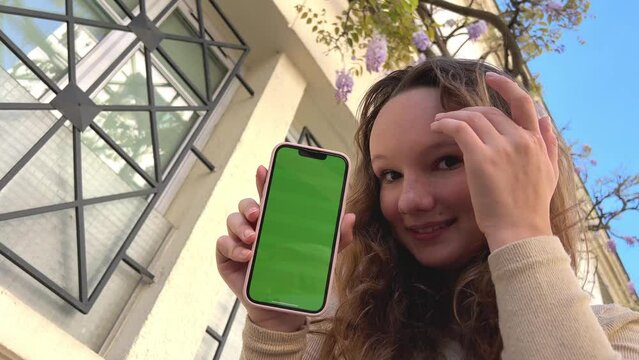 The girl hugs the phone presses her cheek against it green screen and chromate in a pink case the girl smiles and shrugs her shoulder. High quality 4k footage