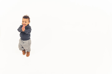 handsome toddler standing on the floor applauding and smiling. High quality photo