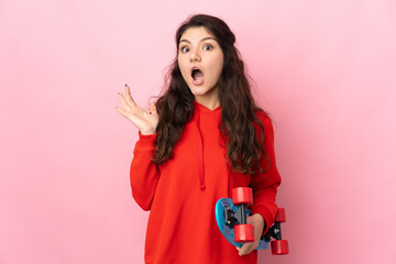 Teenager Russian girl isolated on pink background with a skate and doing surprise gesture