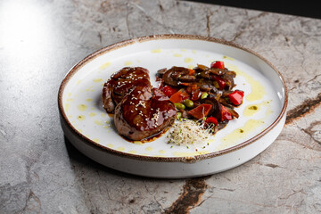 Grilled meat fillet steak wrapped in bacon medallions with raspberry sauce, served with vegetables and mushrooms