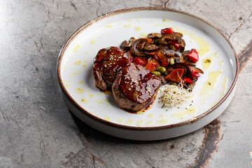 Grilled meat fillet steak wrapped in bacon medallions with raspberry sauce, served with vegetables and mushrooms