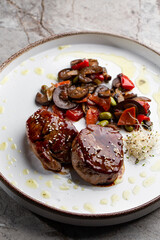 Grilled meat fillet steak wrapped in bacon medallions with raspberry sauce, served with vegetables and mushrooms