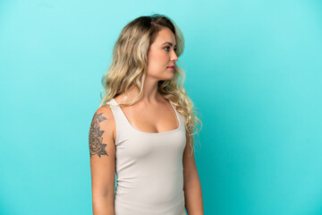 Fototapeta premium Young Brazilian woman isolated on blue background looking to the side