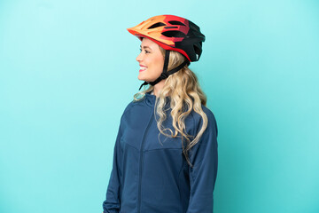 Young cyclist woman isolated on blue background looking side