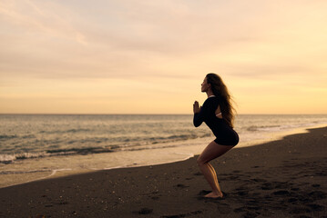 woman doing a yoga practice at the beach while a beautiful sunset