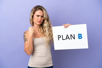 Young Brazilian woman isolated on purple background holding a placard with the message PLAN B and angry