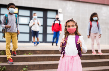 Portrait of tween schoolgirl in protective face mask with rucksack on her way to college on warm fall day. Back to school after lockdown concept.