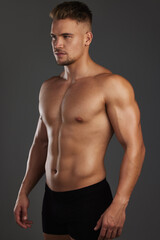 Fototapeta premium Focused on his fitness goals. Cropped shot of a handsome and athletic young man posing shirtless in studio against a dark background.