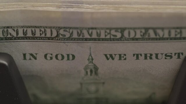 In God we trust on the dollar currency while on a money counting machine