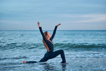 woman doing a yoga practice at the beach while a beautiful sunset