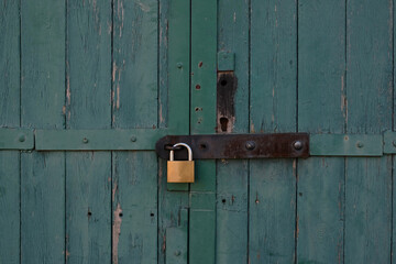 Vintage blue wooden painted door of old building. Shabby door boards. Old peeling painted door, crumbles. Rusty metal lock on the door. Threadbare Wooden rustic background.