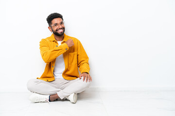 Young Brazilian man sitting on the floor isolated on white background celebrating a victory