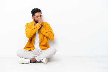 Young Brazilian man sitting on the floor isolated on white background is suffering with cough and feeling bad