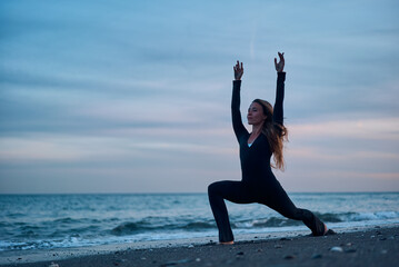 woman doing a yoga practice at the beach while a beautiful sunset