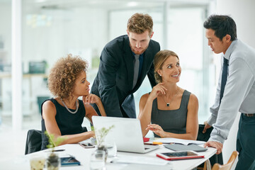 The hardest working team in business. Shot of a group of businesspeople working on a laptop together in a modern office.