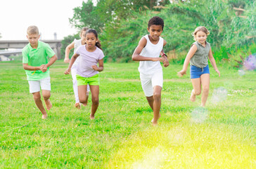 Fototapeta na wymiar Group of five happy children who are jogging in a park on a sunny day