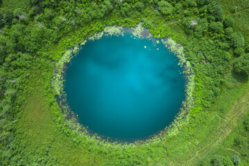 Aerial top down amazing lake of round shape. Cloudy sky reflected in clear turquoise water of pond...