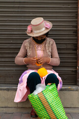 Portrait of a Peruvian woman sewing with wool. Working on the street with a wool pompom.