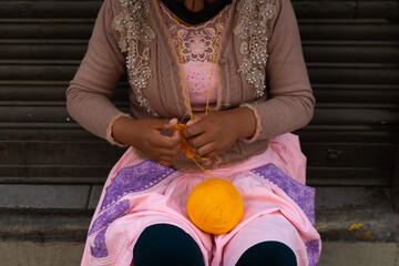 Portrait of a Peruvian woman sewing with wool. Working on the street with a wool pompom.
