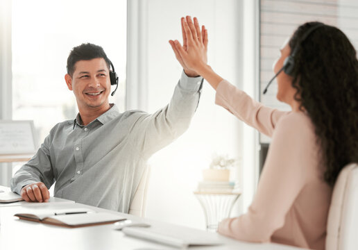 Great job. Shot of two young call center agents giving each other a high five in an office at work.