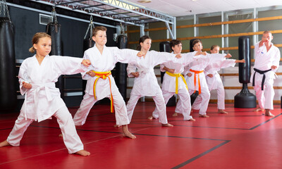 Children wearing karate uniform fighters poses in white kimono, group training