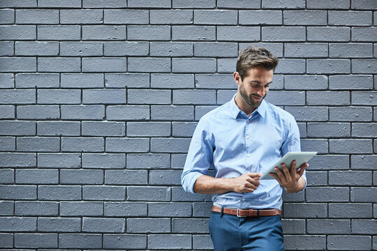 Hes got the look. Shot of a handsome young businessman standing against a grey facebrick wall.