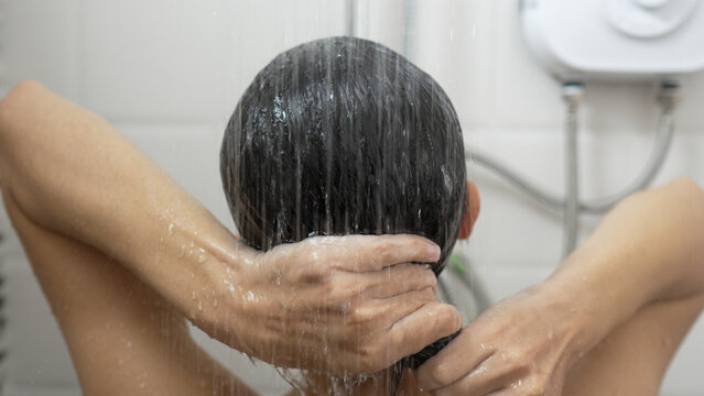 Young woman taking a shower and washing her hair in the bathroom