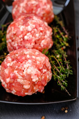 Raw minced pork.meat balls. Minced meat balls with sprigs of thyme on a black plate on a black slate background.Meat products. Farm organic bio meat. 