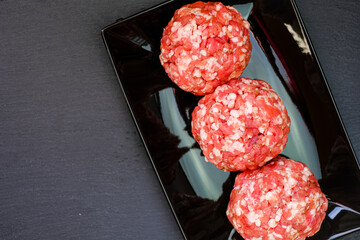 Raw minced pork.meat balls close-up. Minced meat balls on a black plate on a black slate...