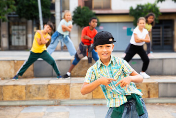 Little boy hip hop dancer exercising with friends at open air dance class