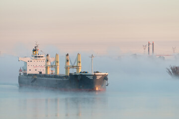 Large bulk cargo ship underway in fog. Foggy big bulker vessel cargo export and import operation.