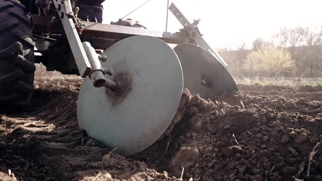 Farmer man works, ploughing in garden chernozem field with motorized unit motoblock - type of small-sized tractor, used in household. Cultivation of land, planting potatoes, plowing soil. Agriculture.