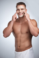 Fototapeta premium Trying to find my place. Studio portrait of an attractive young man applying a beauty treatment to his face against a grey background.