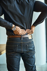 His back muscles are getting tense and tight. Shot of a young businessman suffering from back pain...
