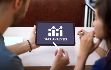 People working with data analysis tool. Young man and woman holding tablet showing infographics chart concept.