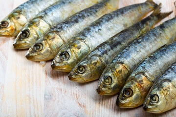 Fototapeta premium Closeup of marinated sardines lined in row on wooden table. Sea delicacy