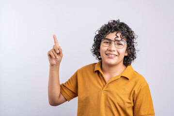 Teenage boy smiling and looking at the camera while pointing to the side on a white background.